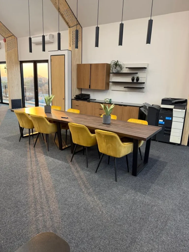 Upstairs boardroom at the Seventh Star venue with a timber table, mustard velvet chairs and pendant lighting, with glass doors at the far end