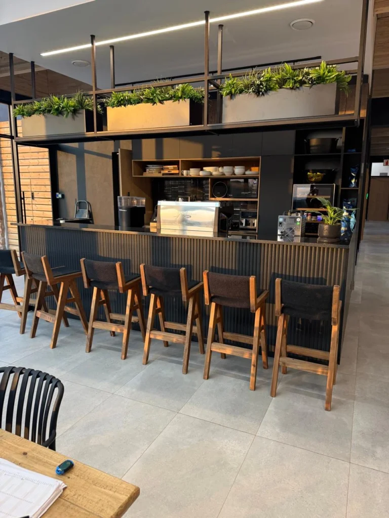 Coffee bar at the Seventh Star venue with a ribbed dark counter, timber bar stools, an espresso machine and hanging planters above the counter