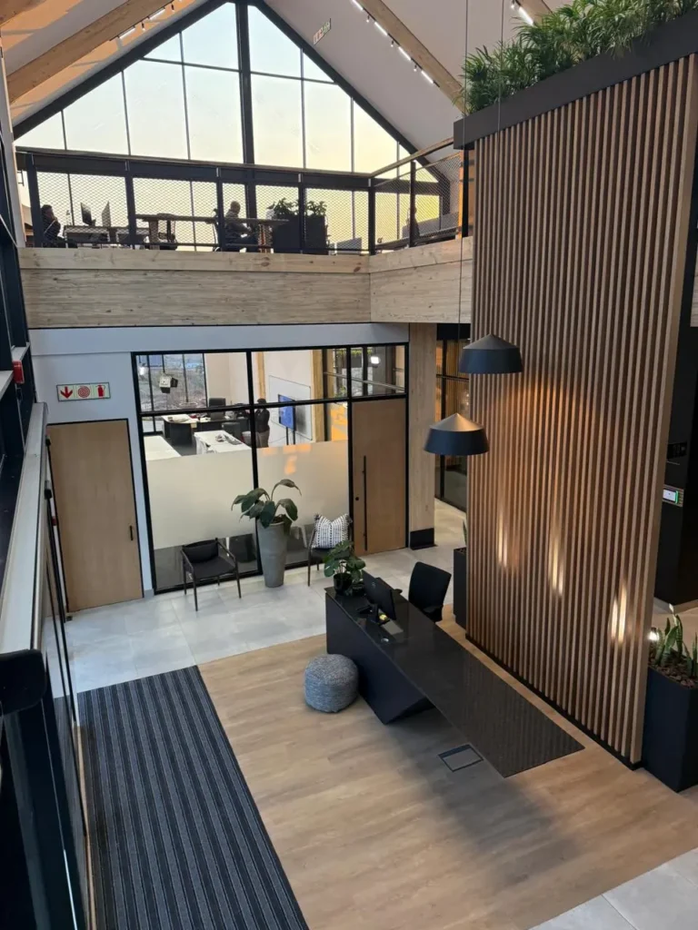 View from the mezzanine at the Seventh Star venue looking down over the reception desk and entrance hall, with a timber slat wall, pendant lights and the pitched roof above