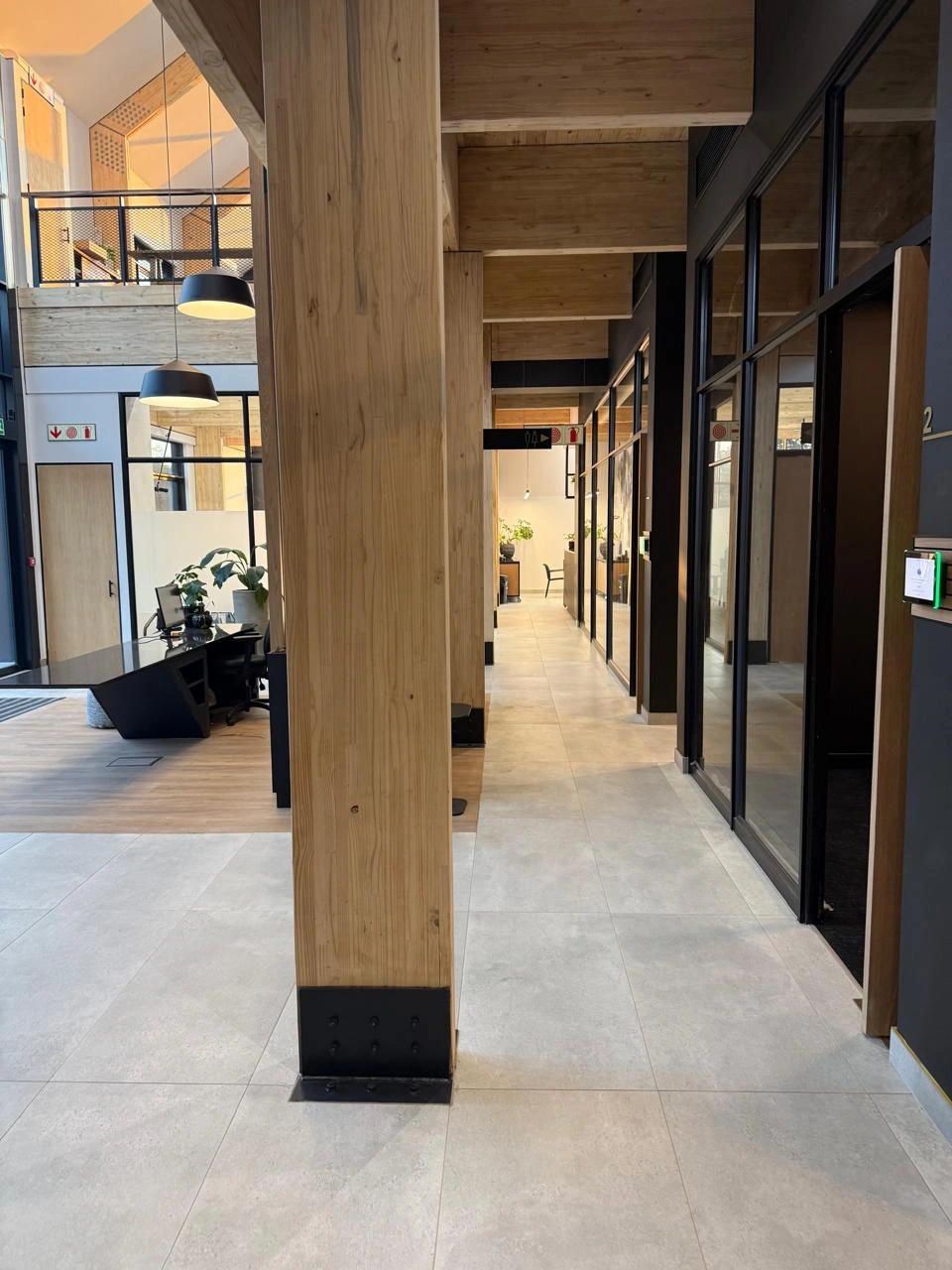 Corridor at the Seventh Star venue running past glass-walled meeting rooms, with a timber column in the foreground and the reception area beyond