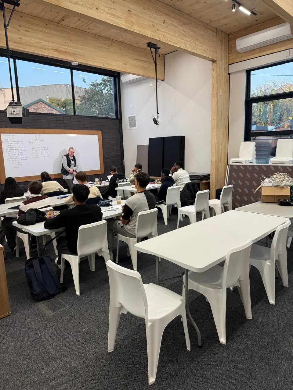 Delegates seated at tables during a training session at the Seventh Star venue, with a facilitator presenting at a whiteboard beneath an exposed timber ceiling